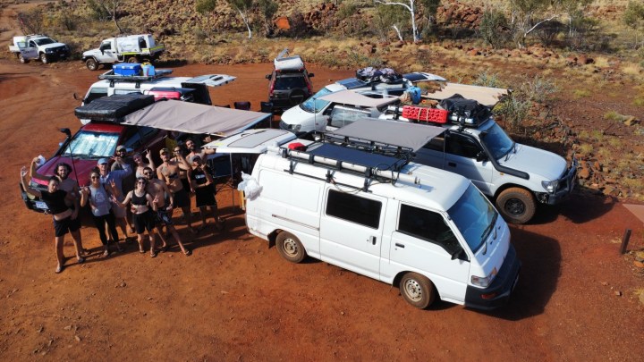 Amici backpacker insieme ai fuoristrada e a un van su terra rossa nel Pilbara